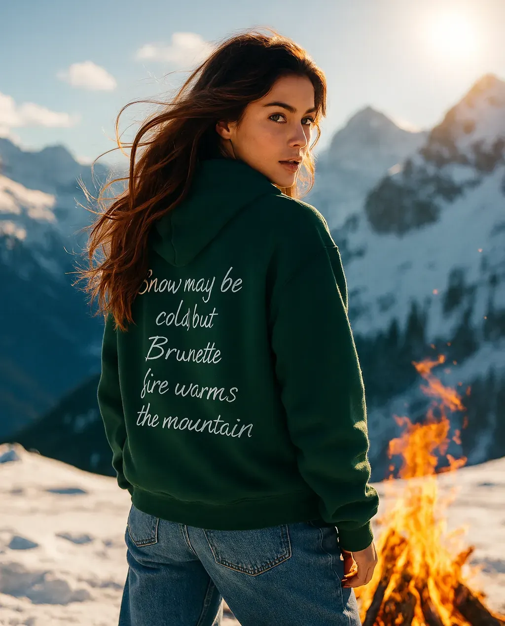 Immagine di una ragazza mora accanto a un falò sulla neve con la felpa verde